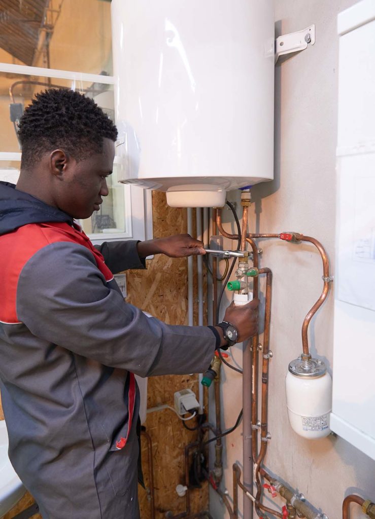 Etudiant qui fait de la plomberie sur un chauffeau